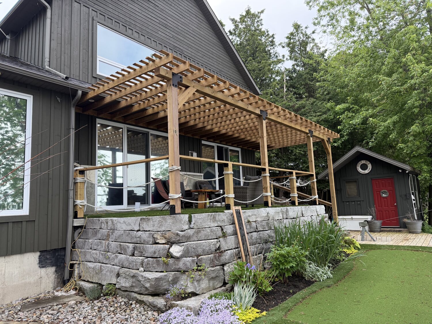 Timber-frame pergola over a stone patio at a Chemong Lake property by Cottage Life Care