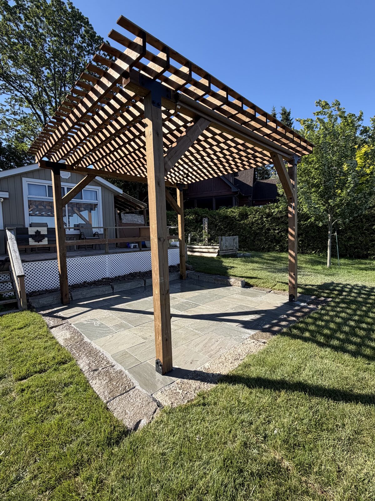 Cedar pergola over a new flagstone patio at a Chemong Lake property by Cottage Life Care